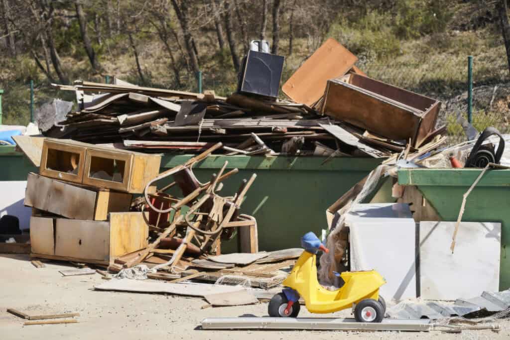 Best Dumpsters for Garage Cleanouts 2 Discarded furniture and household items in a large outdoor trash bin.