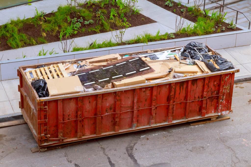 Mixed renovation debris loaded evenly in a roll-off dumpster to avoid overweight fees