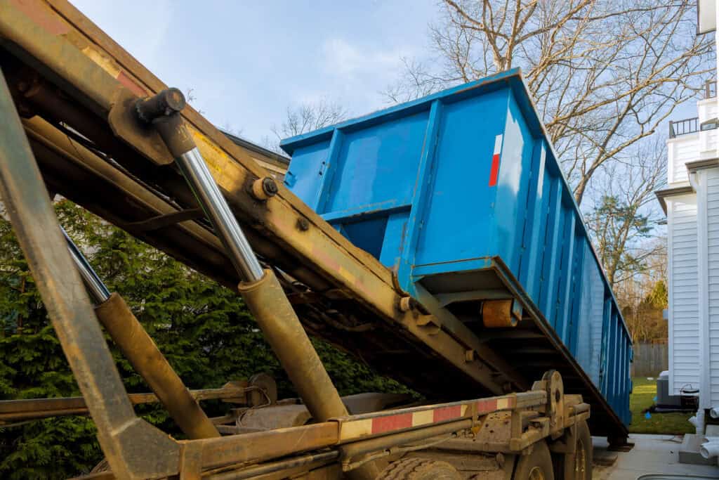 Best Dumpsters for Garage Cleanouts 1 Heavy-duty blue dumpster on a flatbed truck for waste disposal and recycling services.