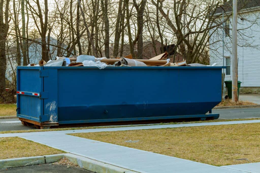 What Fits in a 30 Yard Dumpster? 1 Large blue dumpster filled with construction debris on a suburban street.