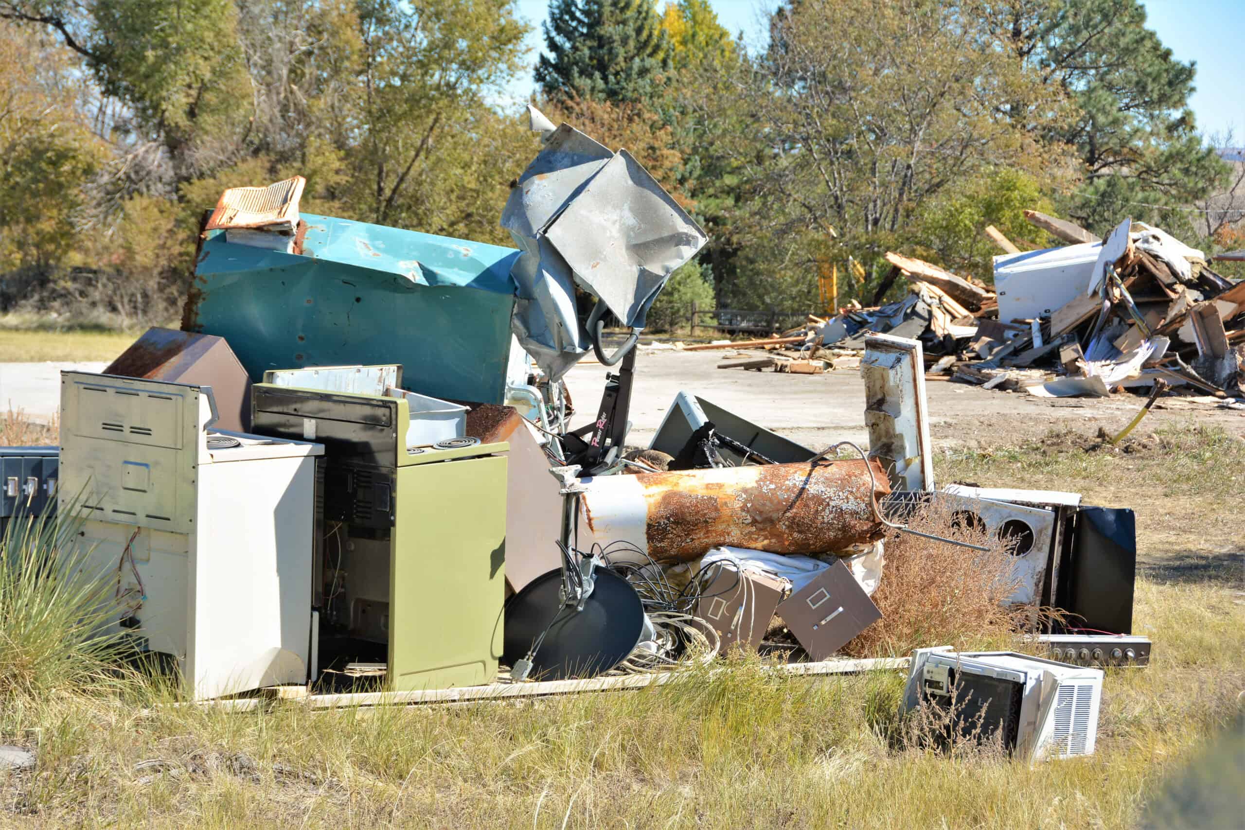 Pile of broken and discarded electronics and appliances outdoors.