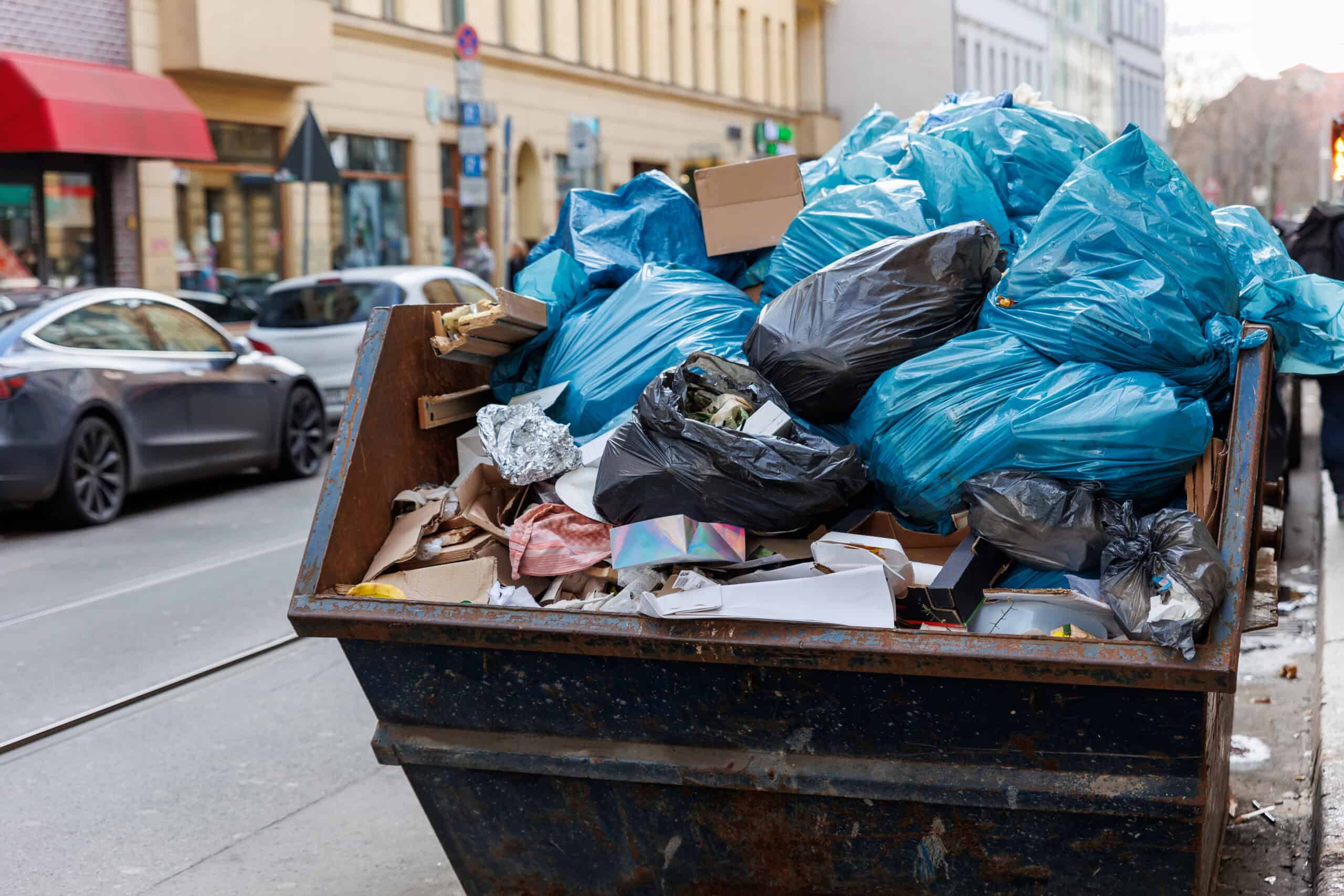 Dumpster Permit Rules in the Cedar Valley 1 Overflowing dumpster with trash bags and debris on city street.