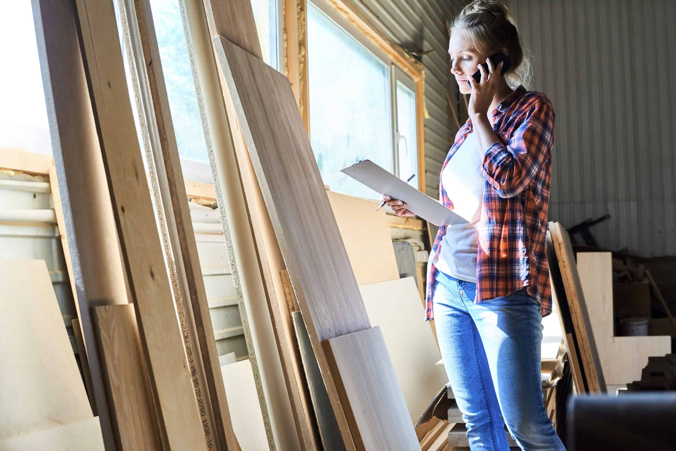 How to Choose a Dumpster Rental Company in Iowa 1 Young woman in woodworking shop talking on phone and holding a tablet.