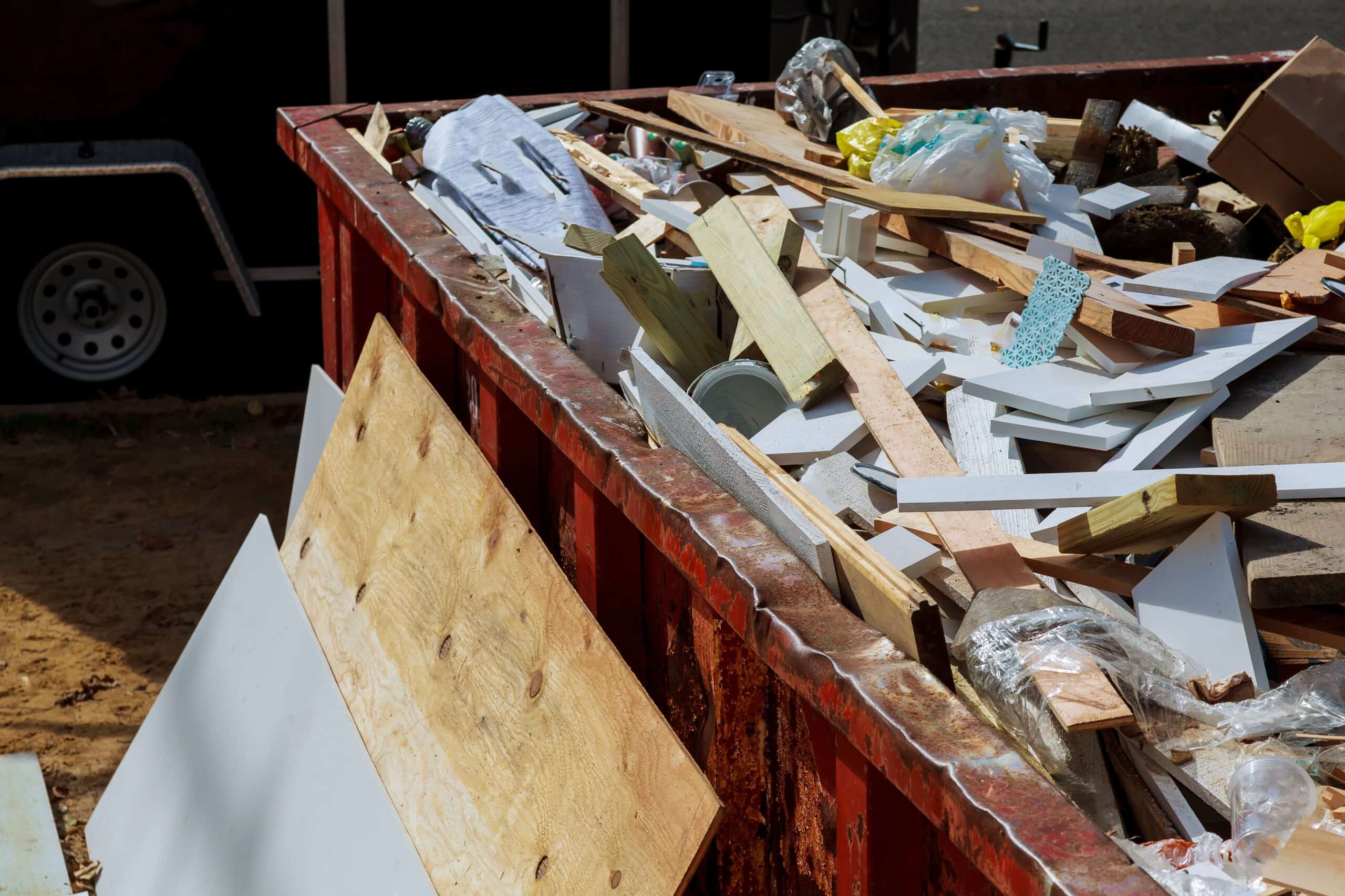 Construction debris and waste materials in a dumpster at a construction site.