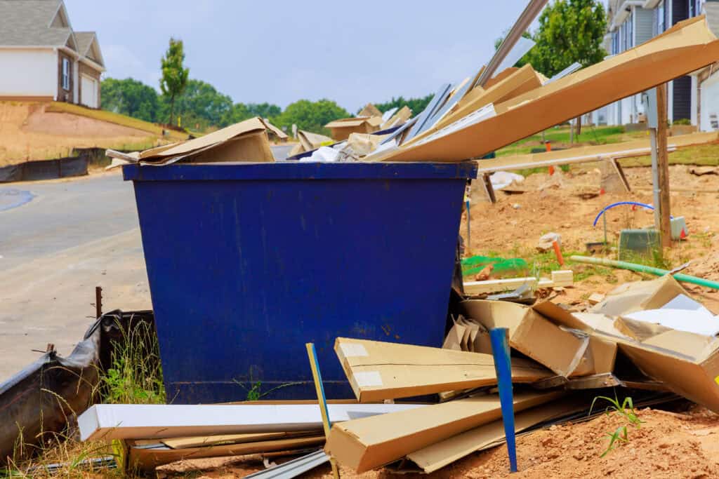 Loading construction debris into a 20-yard dumpster by hand.